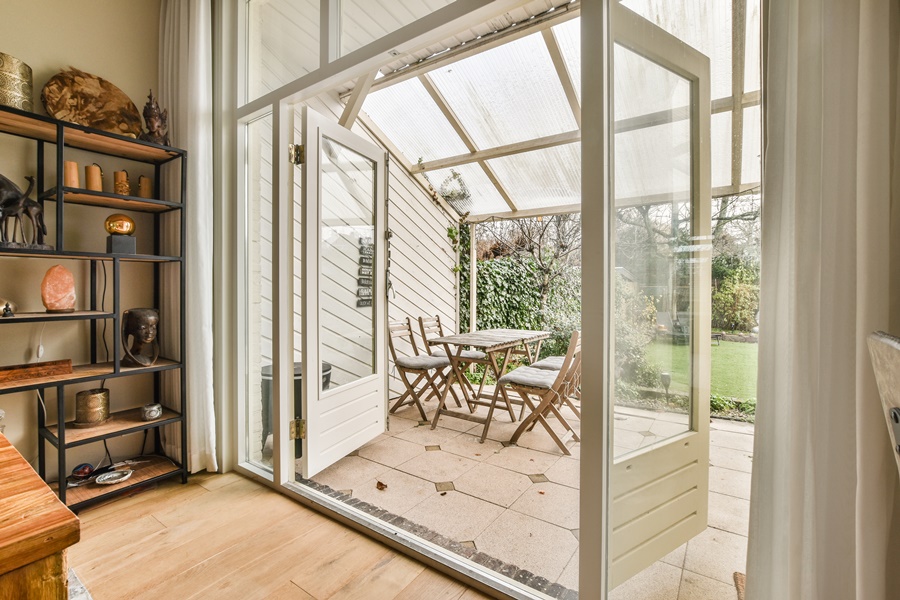 Comedor exterior techado con cerramiento de cristal parcial en una vivienda, diseñado para ahorrar energía con cerramiento de cristal y aprovechar la luz natural durante todo el año.