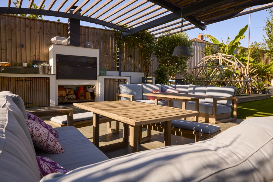Patio exterior con pérgola de madera y zona de comedor al aire libre, ideal para disfrutar de los beneficios de las pérgolas en climas soleados.