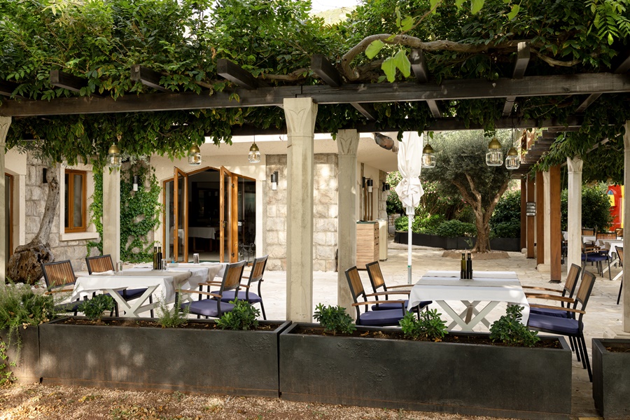 Restaurante con pérgola cubierta de vegetación natural, una solución estética y funcional que demuestra los beneficios de las pérgolas en hostelería.