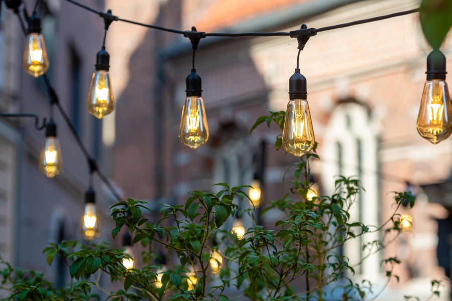 Guirnalda de bombillas LED estilo vintage iluminando una terraza urbana, ejemplo de iluminación exterior para terrazas decorativa y eficiente.