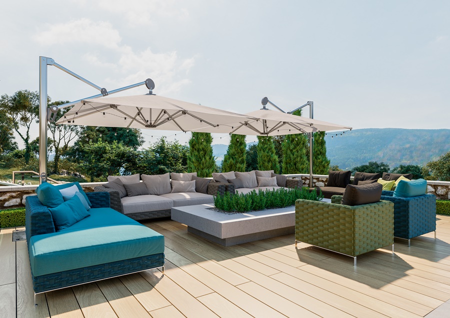 Amplia terraza con suelo de madera, sofás modulares y un sistema de toldo de brazo lateral doble. Ilustración de cómo poner un toldo en una terraza grande con vistas al entorno natural.